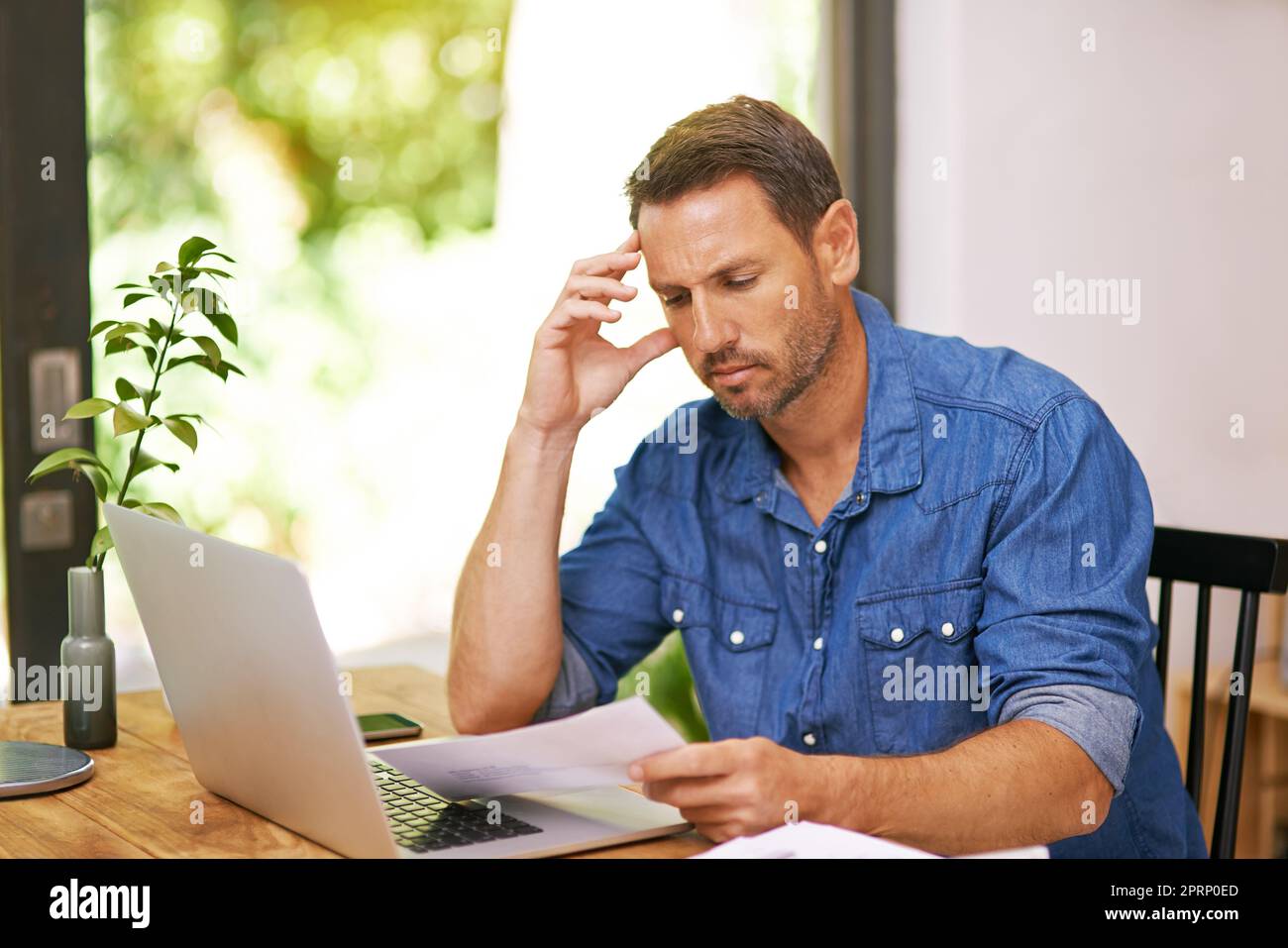 Sein kleines Unternehmen von zu Hause aus zu verwalten. Ein Mann, der sich während der Arbeit von zu Hause aus einen Papierkram ansieht. Stockfoto