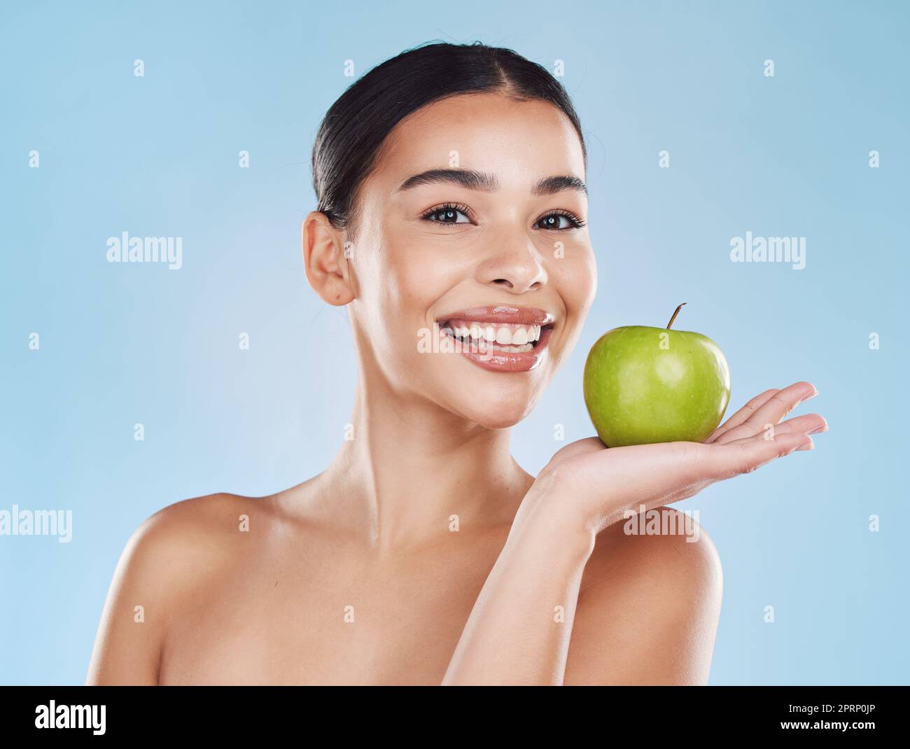 Wellness, Gesundheit und Schönheit mit Frau und einem Apfel für Ernährung, Entgiftung und grüne Diät vor blauem Hintergrund. Ernährungsberater, Lächeln und Obst mit glücklicher Frau, die gesund für einen natürlichen Lebensstil essen Stockfoto