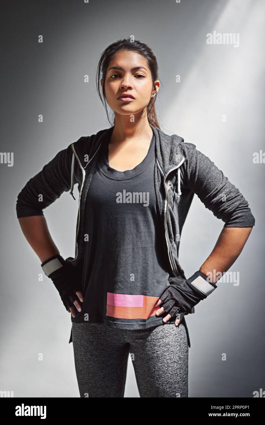 Motiviert, ihre Fitnessziele zu erreichen. Porträt einer jungen Frau in Sportkleidung, die vor grauem Hintergrund posiert. Stockfoto