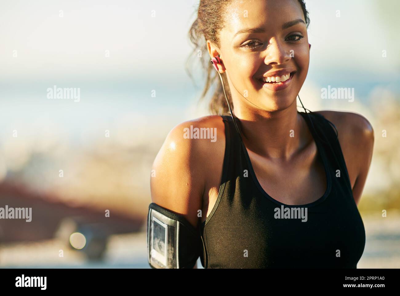 Fitness bringt mir immer ein Lächeln ins Gesicht. Eine junge Frau trainiert im Freien. Stockfoto