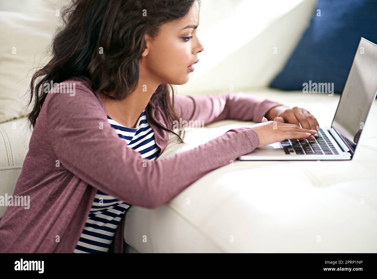 Arbeiten an dem neuesten Artikel für ihren Blog. Eine junge Frau mit ihrem Laptop zu Hause. Stockfoto