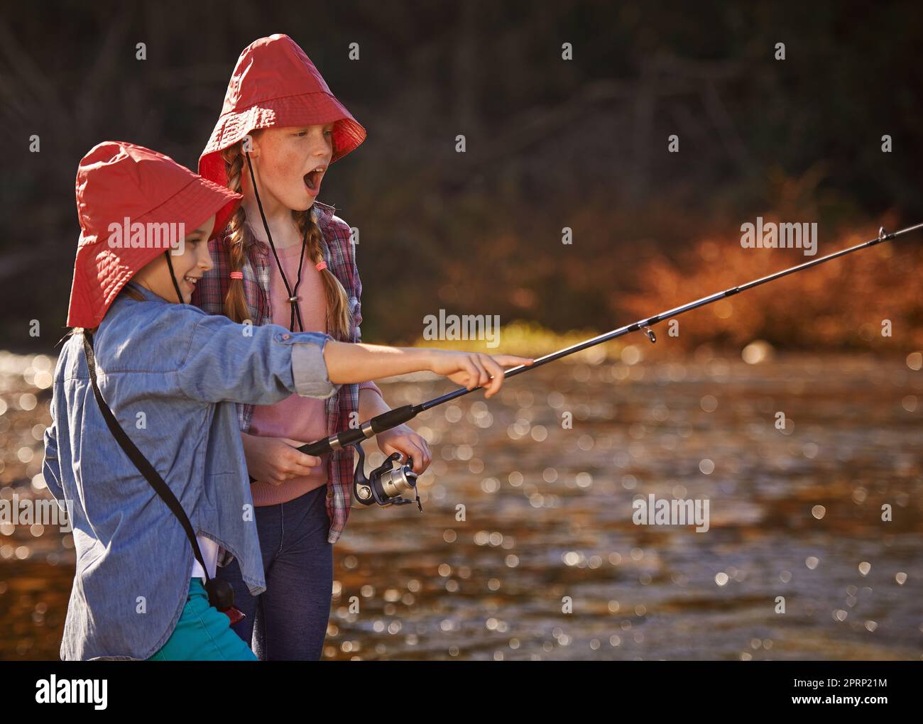 Oh mein Gott, seine riesige. Zwei junge Mädchen, die an einem Fluss fischen. Stockfoto