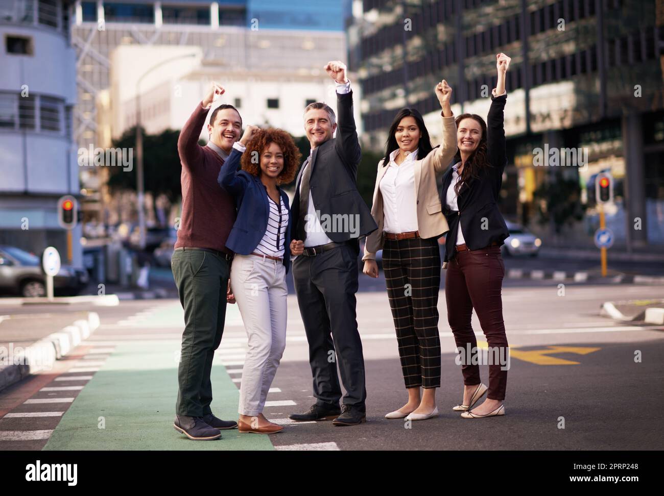 Das beste Team der Stadt. Ein motiviertes Business-Team, das seine Hände für den Erfolg hochlegt, während es mitten auf einer Straße steht. Stockfoto