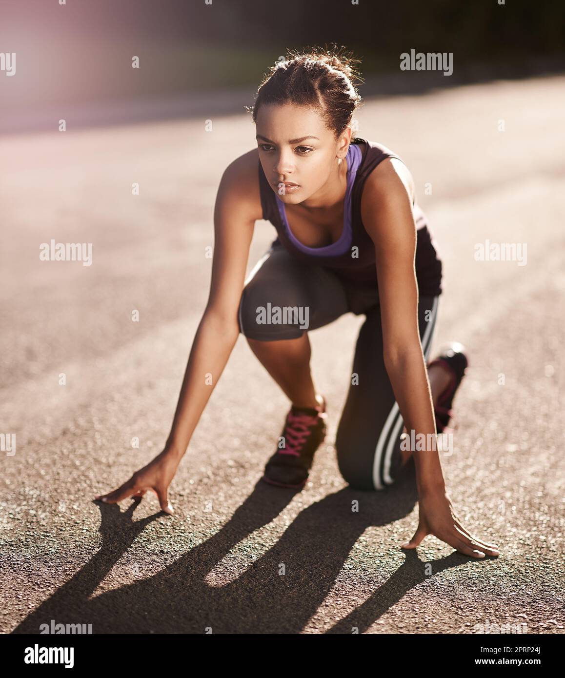 Fitness ist ein Lebensstil ohne Ziellinie. Eine junge Frau in der Startposition für einen Lauf. Stockfoto