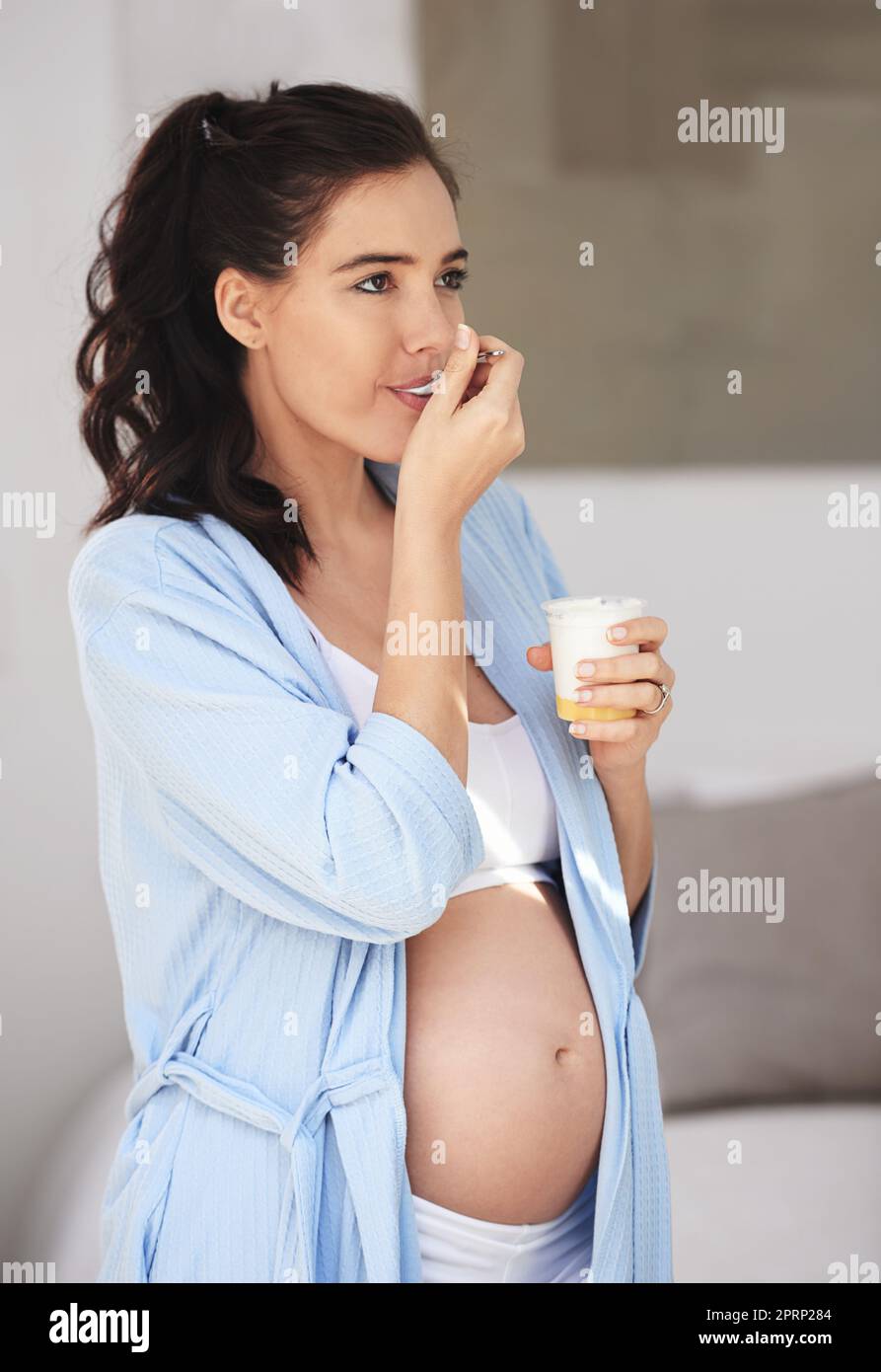 Naschen für zwei Personen. Eine Schwangerin genießt zu Hause einen Snack. Stockfoto