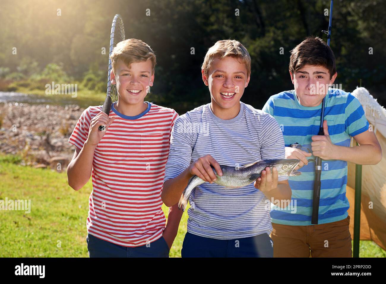 Stolz auf ihren Fang. Porträt von drei jungen, die einen Fisch zeigen, den sie gefangen haben. Stockfoto