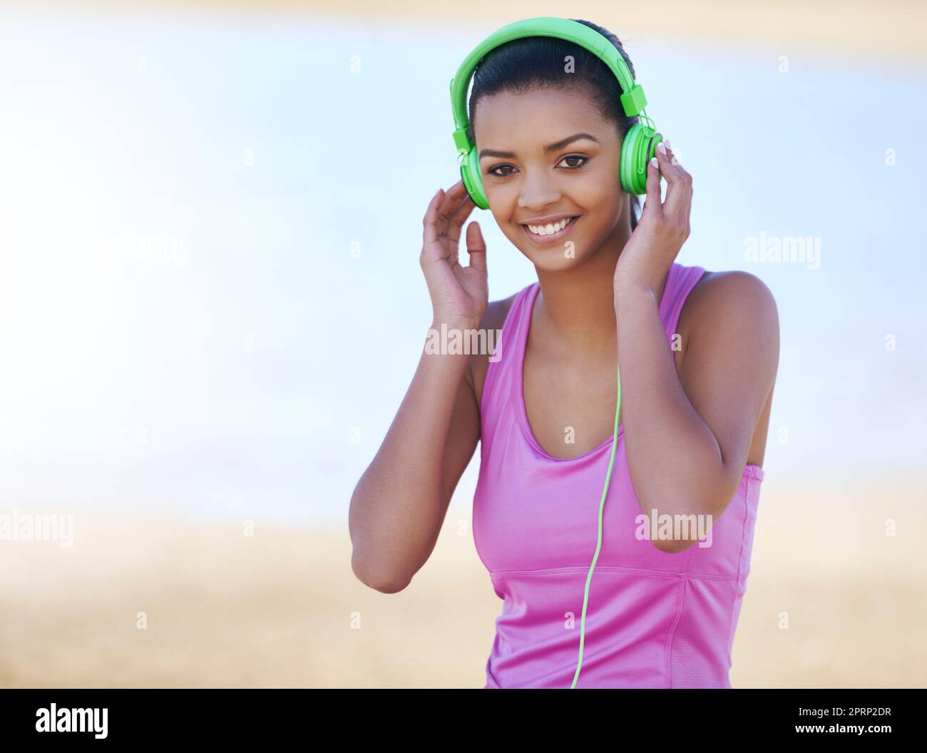 Musik hält mich motiviert. Porträt einer sportlichen jungen Frau, die im Freien Kopfhörer trägt. Stockfoto