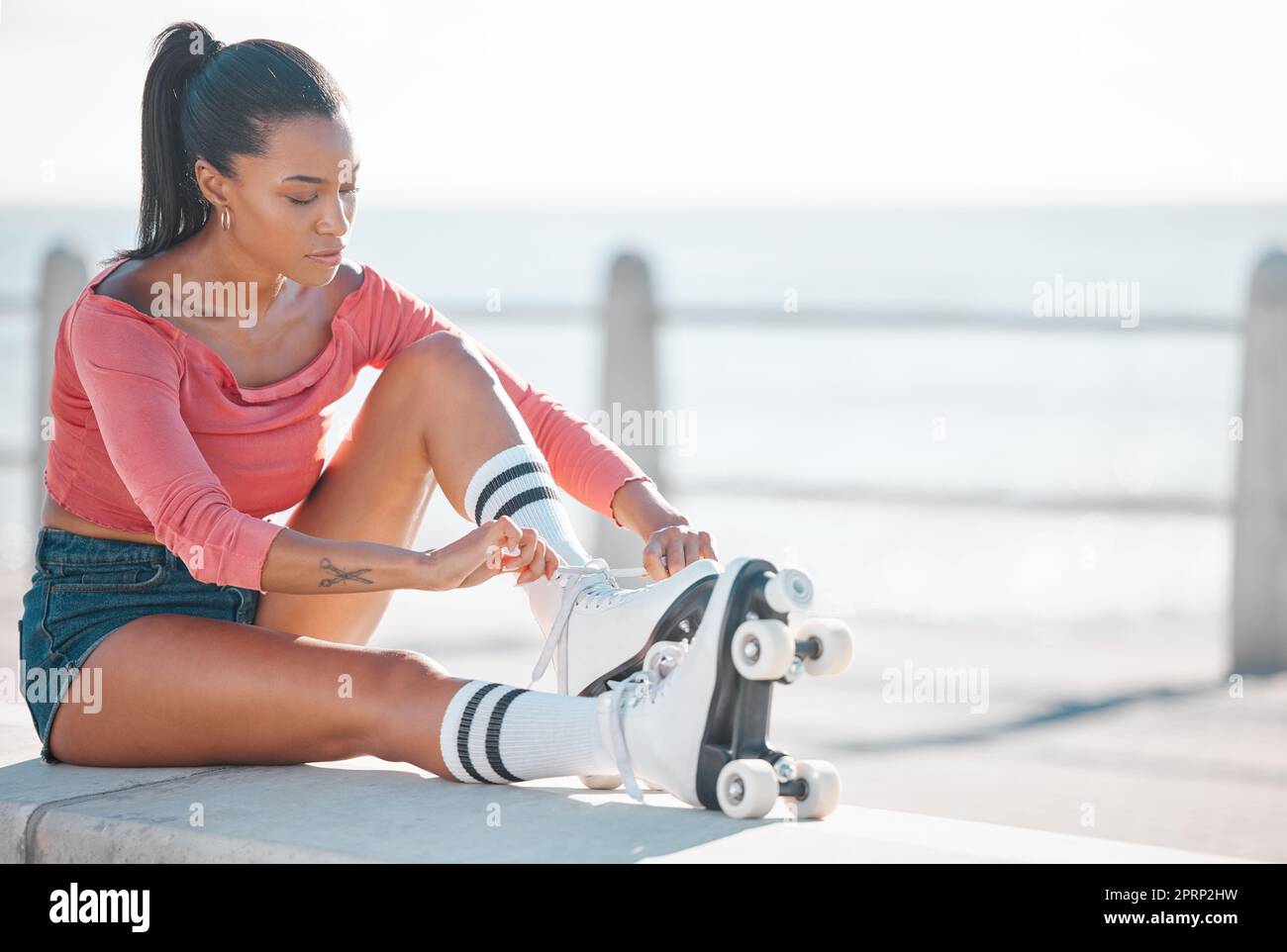 Fitness, Training und glückliche Frauen, die an einem sonnigen Tag am Strand Rollschuhlaufen, Spaß haben, während sie sich auf das Workout im Freien vorbereiten. Aktive Frau genießt Freizeit mit Hobby, Training und Kardio mit Spaß Stockfoto