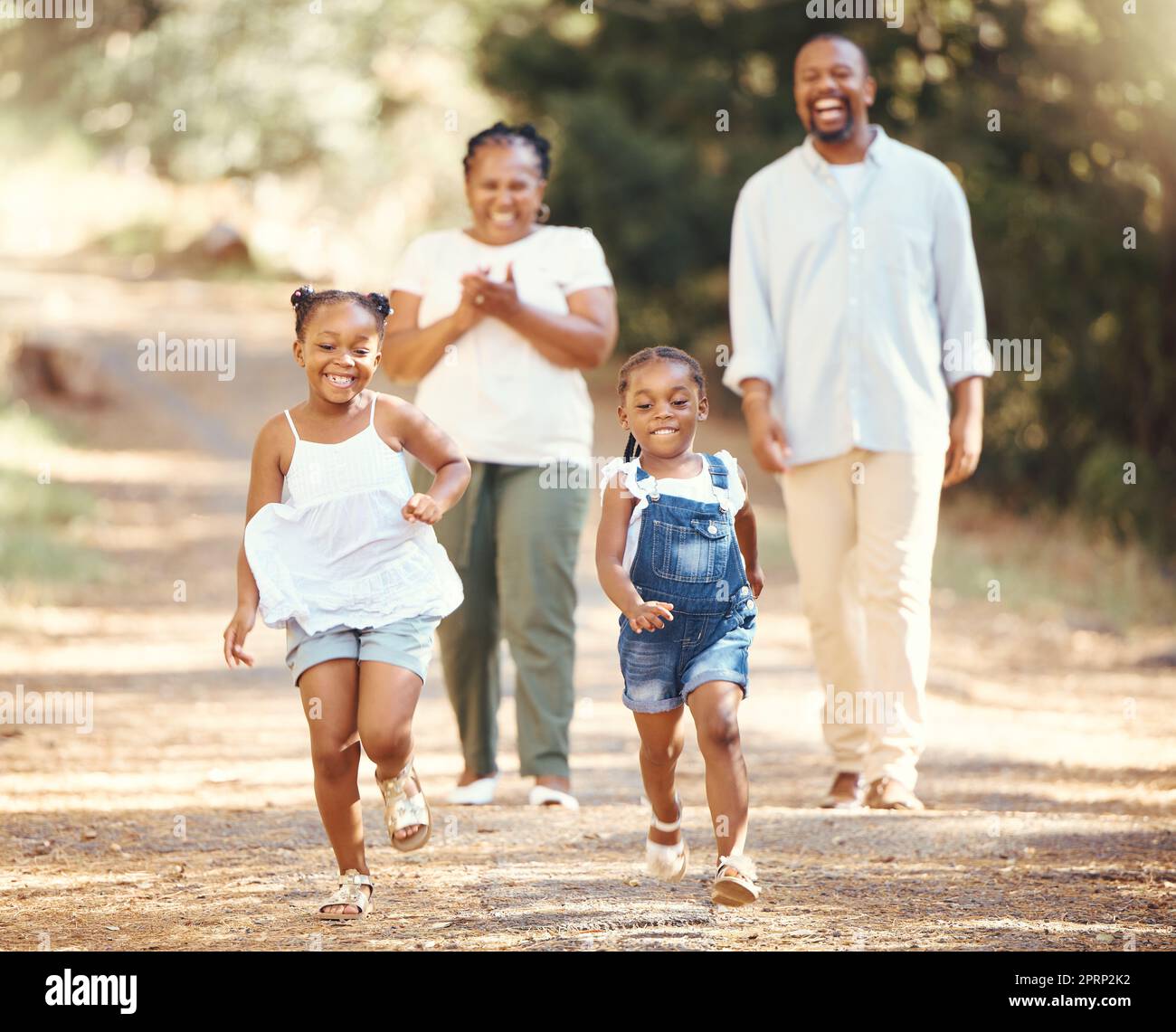 Glückliche, schwarze Familie und Kinder laufen im Sommer im Naturpark, während mom und Dad ihre kleinen afrikanischen Kinder anfeuern. Spielen, Lifestyle und aktive Eltern, die mit ihren gesunden Mädchen in einem Wald wandern Stockfoto