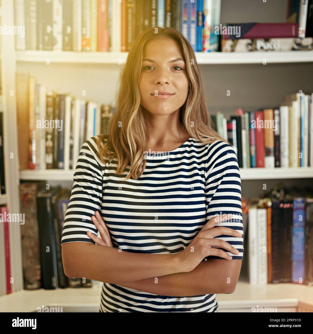 Genießen Sie die Freiheit des Freiberufens. Porträt einer Frau, die in ihrem Heimbüro vor Bücherregalen steht. Stockfoto