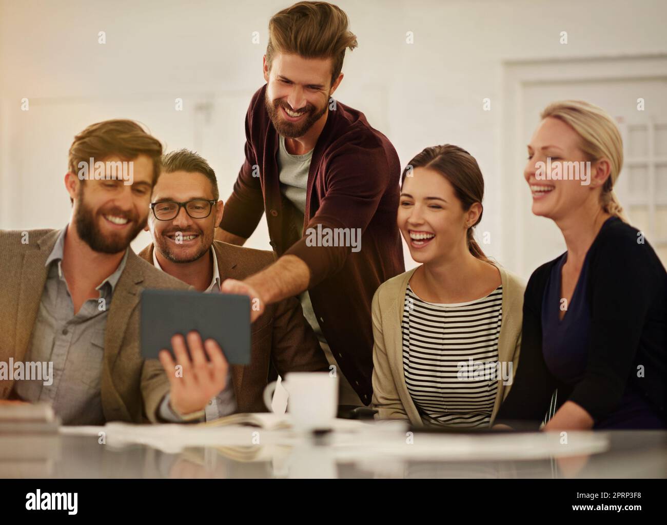 Eine Gruppe von Geschäftsleuten, die im Sitzungssaal ein Tablet betrachten. Stockfoto