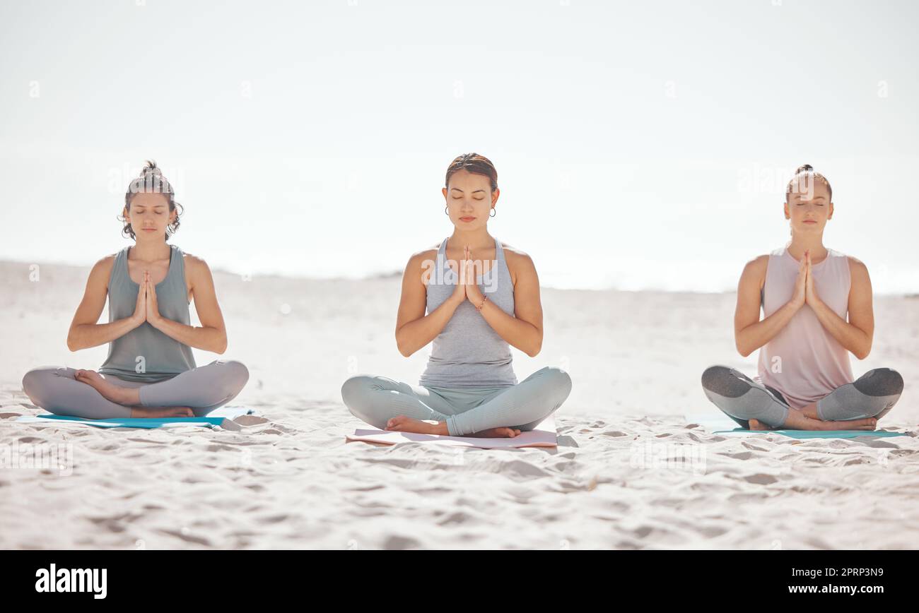 Strandmeditation, Frauen oder Zen-Freunde in der psychischen Gesundheit Wellness Übung, Pilates Training oder Mind reiki Energie Yoga. Entspannen Sie sich, beten Sie Ihre Hände oder trainieren Sie mit friedlichen Atemhilfen auf Sand Stockfoto