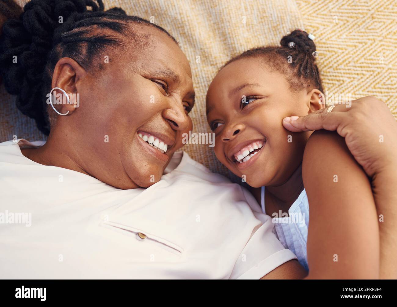Glücklich, lächelnd und Familie einer schwarzen Oma und eines Kindes in Glück, entspannt und zu Hause auf einem Bett liegend. Ältere afrikanische Großmutter und kleines Mädchen in fröhlicher, liebevoller und lächelnder Begeisterung im Schlafzimmer Stockfoto