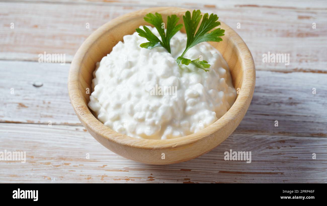 Hüttenkäse in einer Schüssel auf einem hölzernen Hintergrund. Diät und gesunde Ernährung Konzept Stockfoto