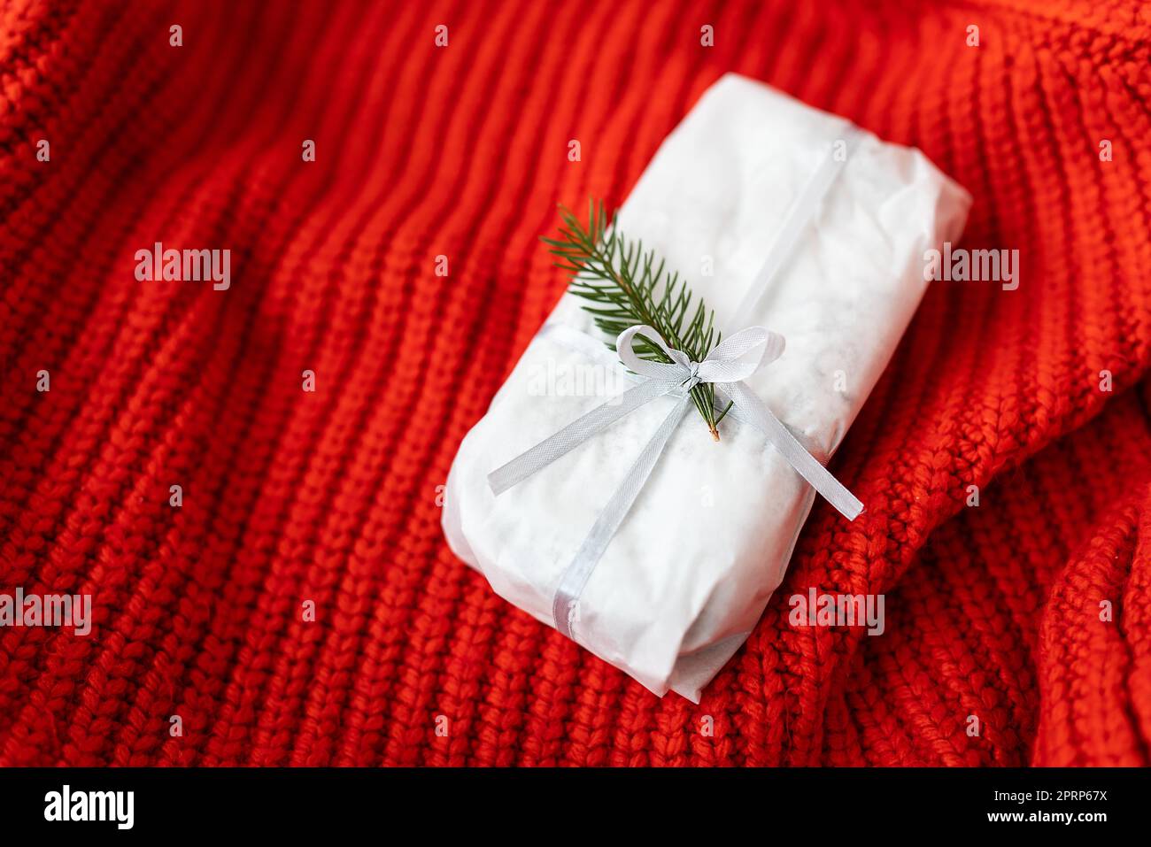 Weihnachtliches deutsches Gebäck mit einem schönen Band und einem Nobilis-Zweig auf rotem Hintergrund. Traditionelles Weihnachtsdessert. Stollen zu Weihnachten. Stockfoto