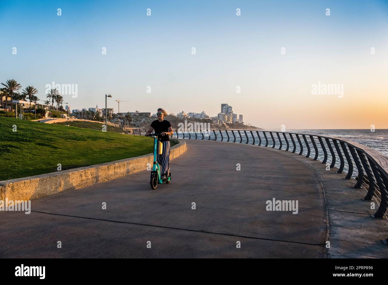 Aktiv jung im Herzen 60s Frau/Frau, die einen Elektroroller auf der Promenade in Tel Aviv Israel benutzt Stockfoto