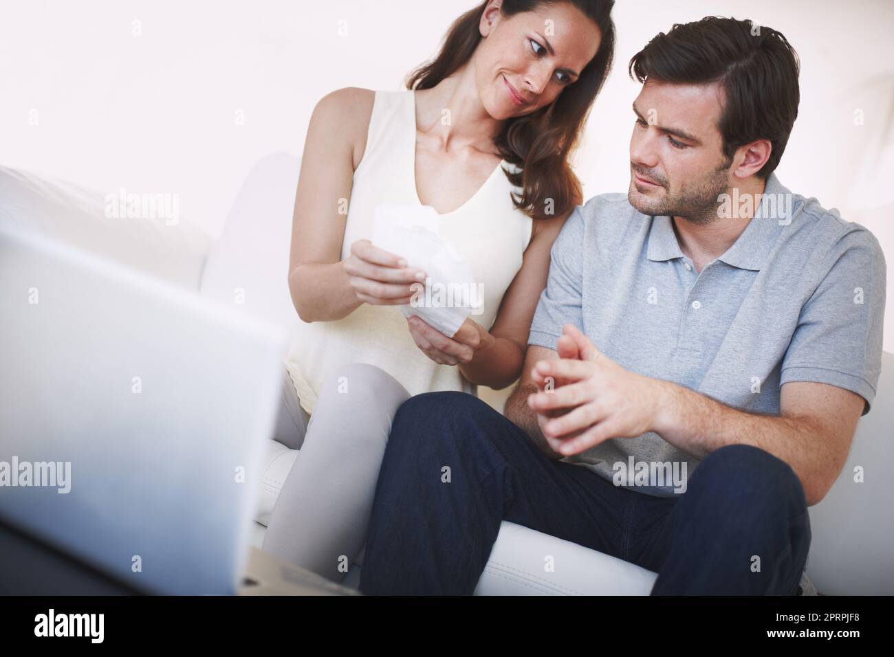 HES stolz auf seine Frau Budgetierung Fähigkeiten. Ein verheiratetes Paar prüft Rechnungen, während sie ihre Hausfinanzen tun. Stockfoto