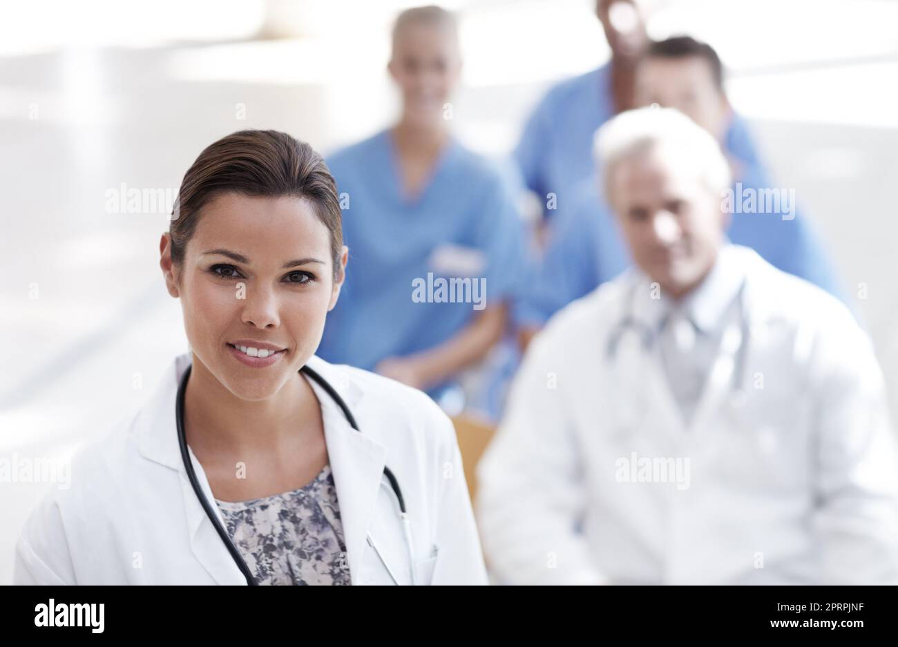 Leidenschaft und Engagement machen sie erfolgreich. Ein Arzt steht mit Kollegen im Hintergrund. Stockfoto