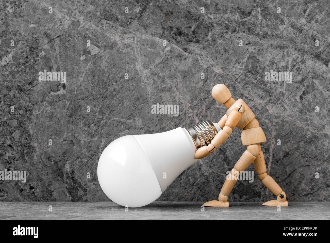 Dummy mit wirtschaftlicher LED-Glühlampe auf Steinhintergrund Stockfoto