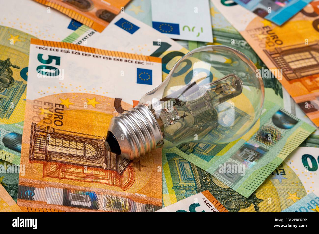 Veraltete unwirtschaftliche und unökologische Glühlampe auf Euro-Banknoten Stockfoto