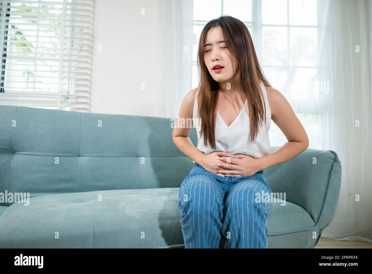 Asiatische junge Frau unglückliche Hände halten auf dem Bauch leiden an Bauchschmerzen Stockfoto