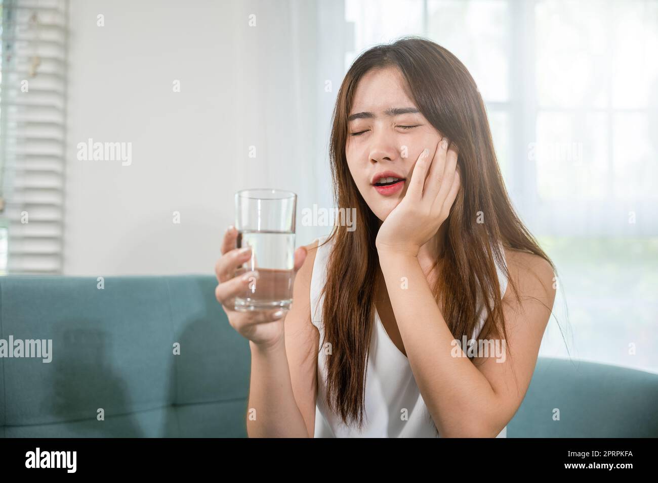 Schöne weibliche Zahnschmerzen und Zahnprobleme beim Wangenberühren Schmerzen nach dem Trinken von kaltem Wasser Stockfoto