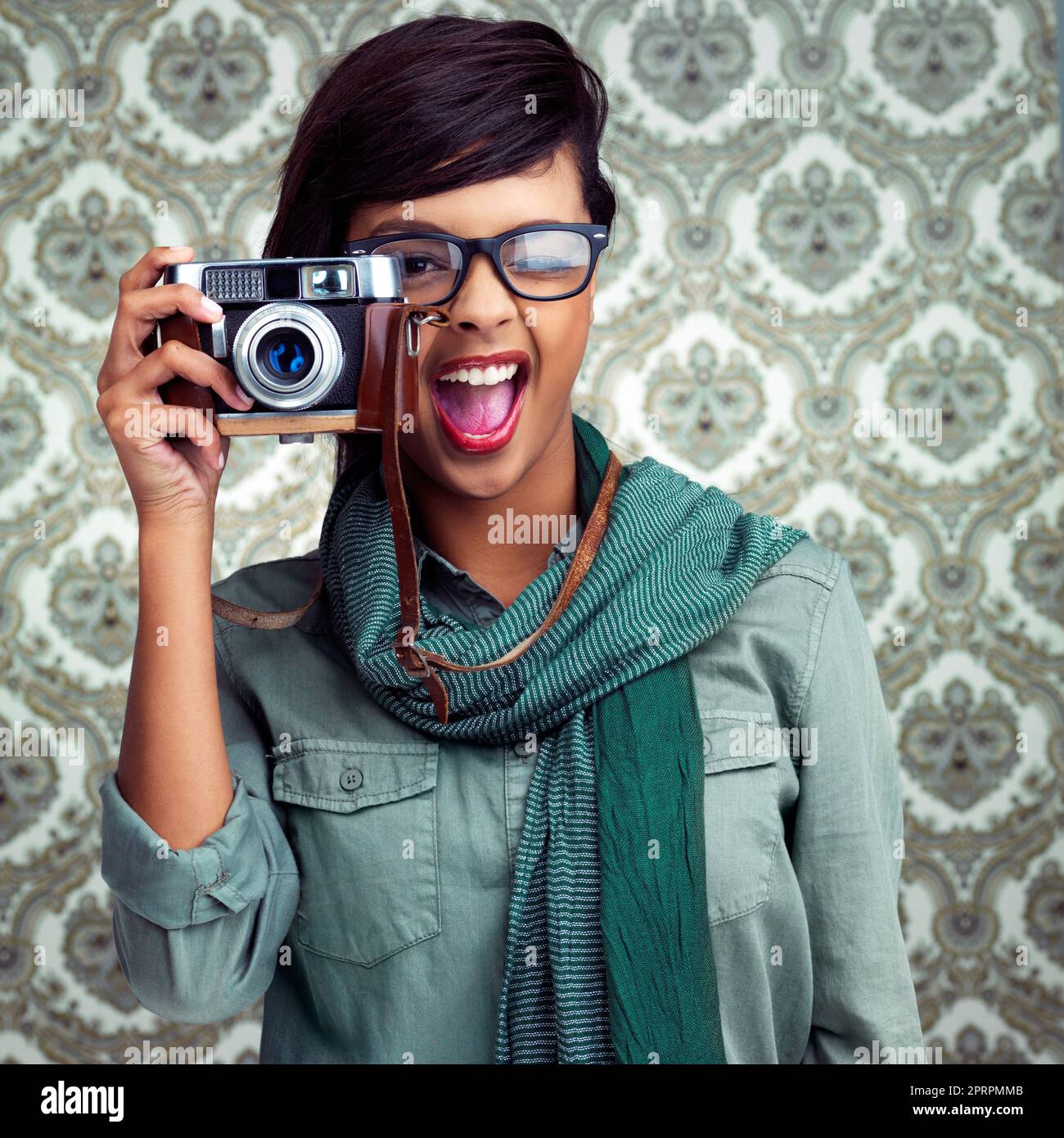 Lassen Sie mich diese Schönheit einfangen: Eine junge Frau, die mit einer Kamera über einem gemusterten Hintergrund posiert. Stockfoto