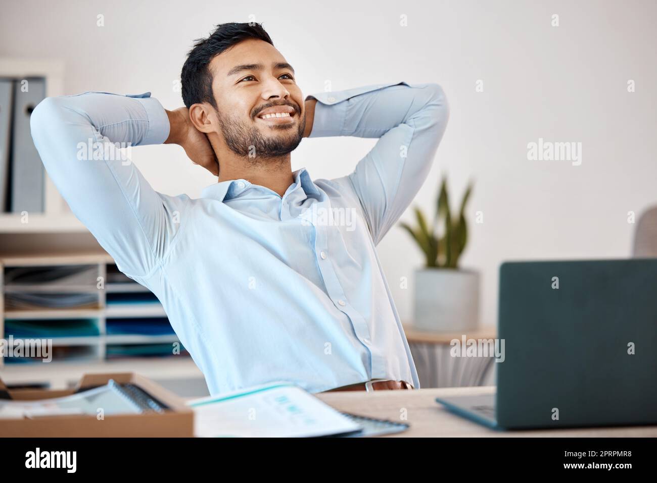 Geschäftsmann, der sich nach Abschluss eines Projekts an einem Schreibtisch im Büro in seiner Geschäftsstelle entspannt. Glücklicher, ruhiger und stressfreier Mitarbeiter, der nach einem erfolgreichen Arbeitstag an seinem Tisch sitzt und sich ausruht. Stockfoto