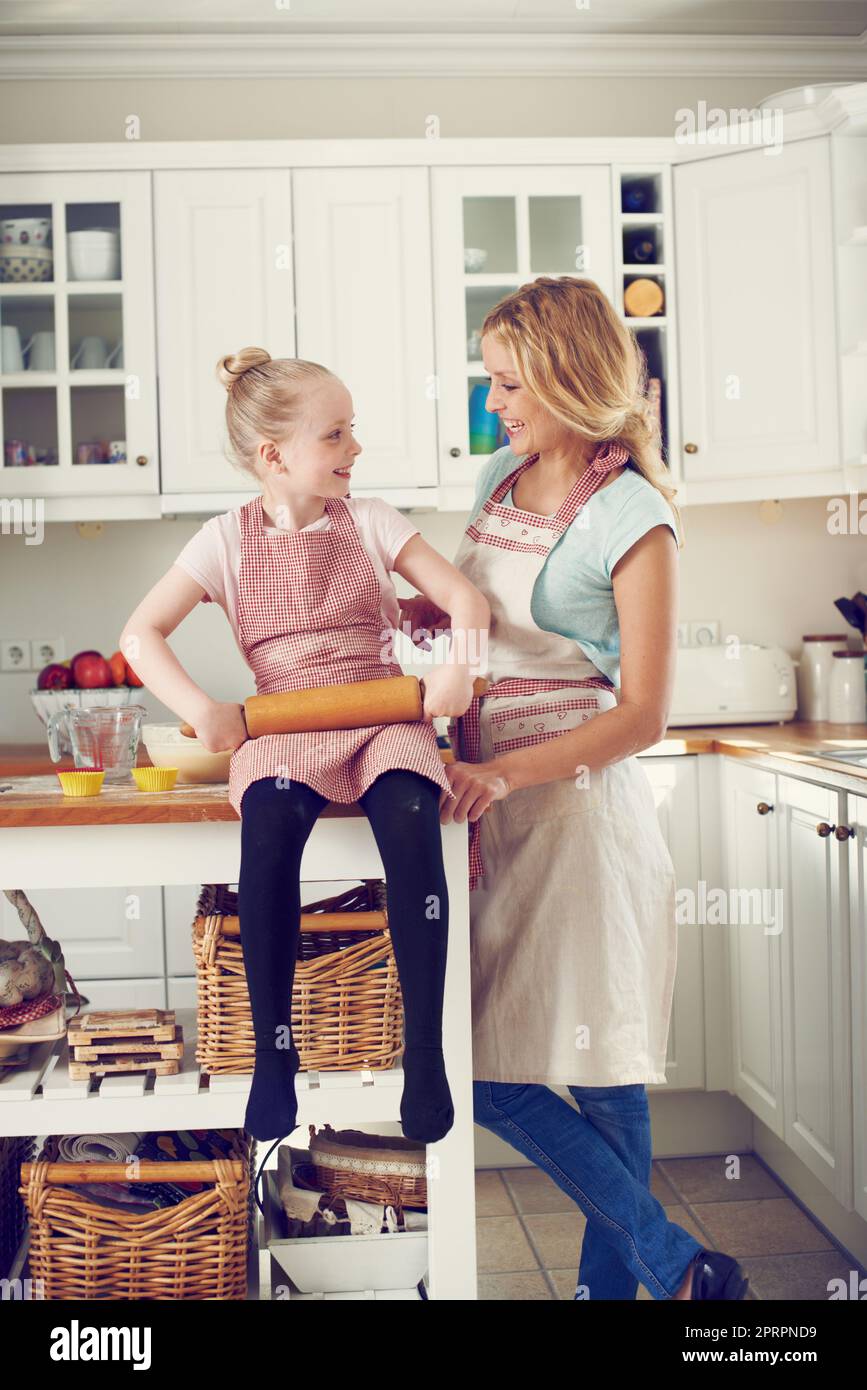 Ich kann es kaum erwarten, einige Backkünste zu erlernen. Nettes kleines Mädchen, das zu Hause mit ihrer Mutter in der Küche backt. Stockfoto