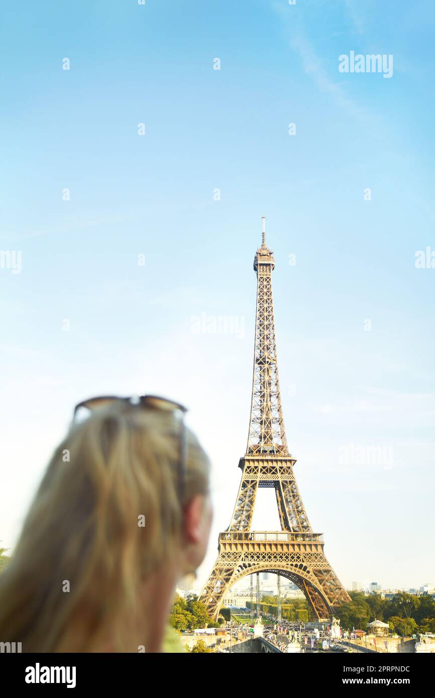 Erleben Sie die Schönheit der Eiffelturm. Rückansicht einer jungen Frau, die im Pariser Stadtbild sah. Stockfoto