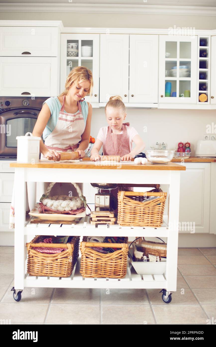 Kleben über etwas Backen. Nettes kleines Mädchen Backen in der Küche mit ihrer Mutter. Stockfoto