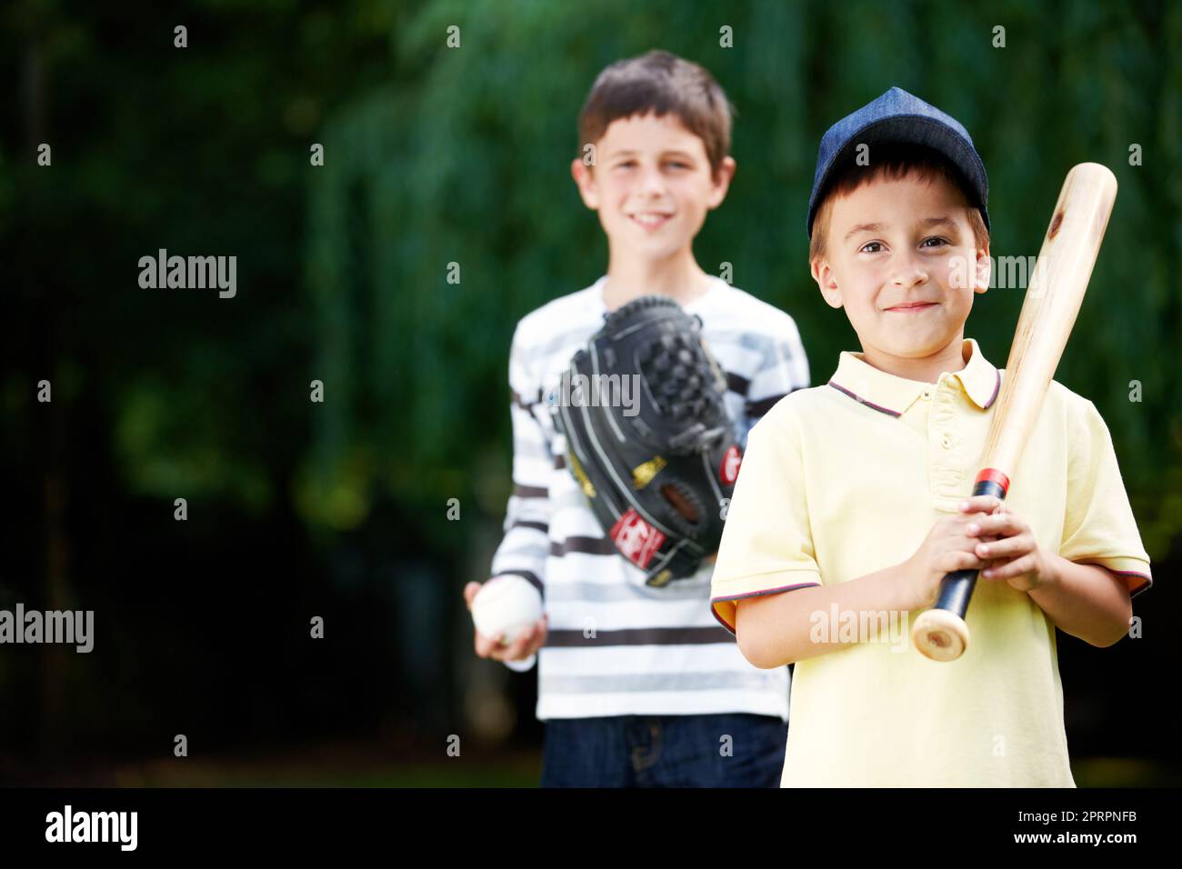 Ich werde einen Heimlauf machen. Zwei junge Jungs lächeln glücklich nach einem energiegeladenen Baseballspiel im Park - Copyspace. Stockfoto