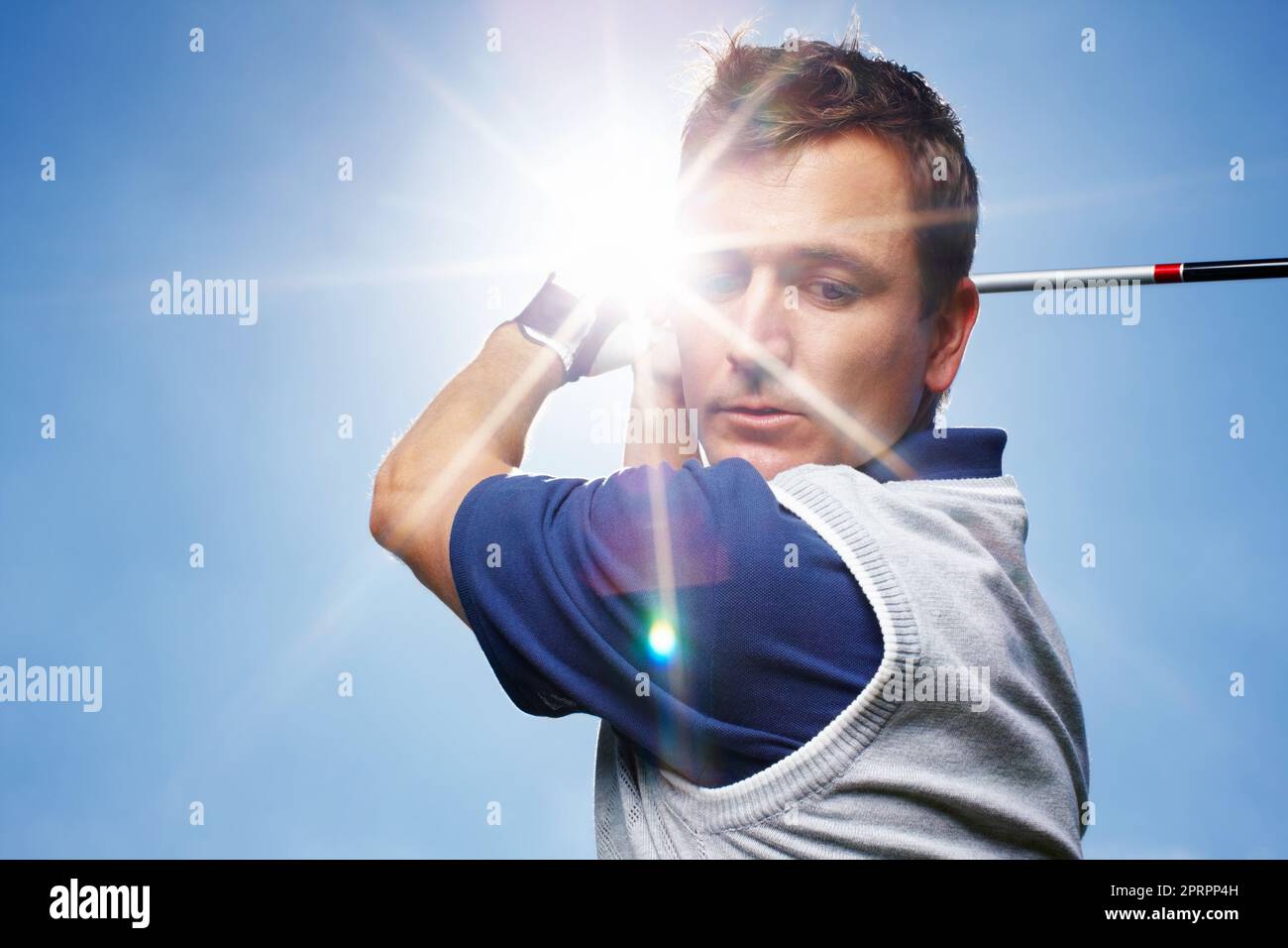 HES konzentrierte sich auf seinen Schwung. Junger Mann in vollem Gange während einer Runde Golf gegen einen blauen Himmel. Stockfoto