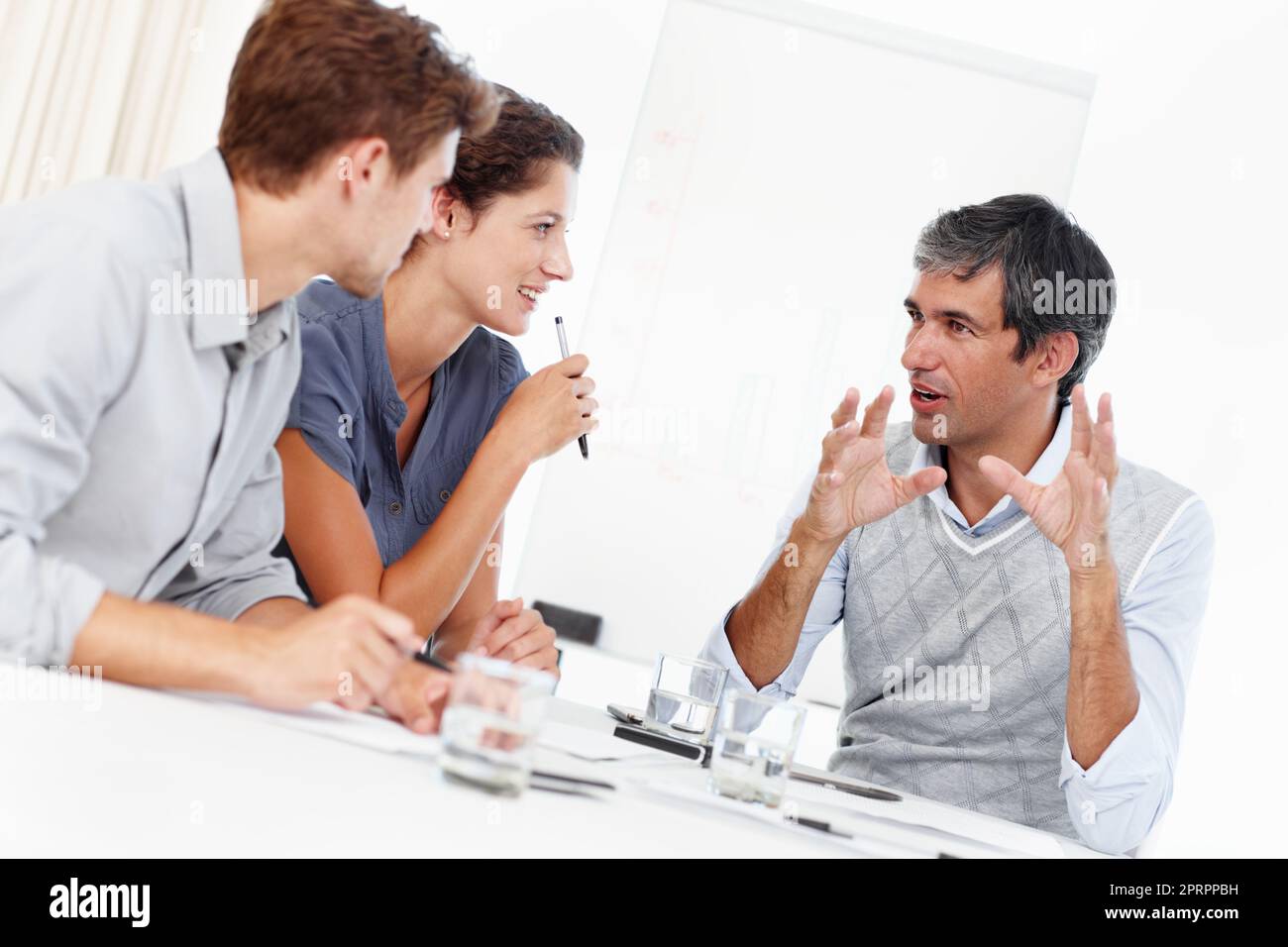 Animierte Geschäftsideen. Drei positiv aussehende Geschäftsleute unterhalten sich in einem Meeting. Stockfoto