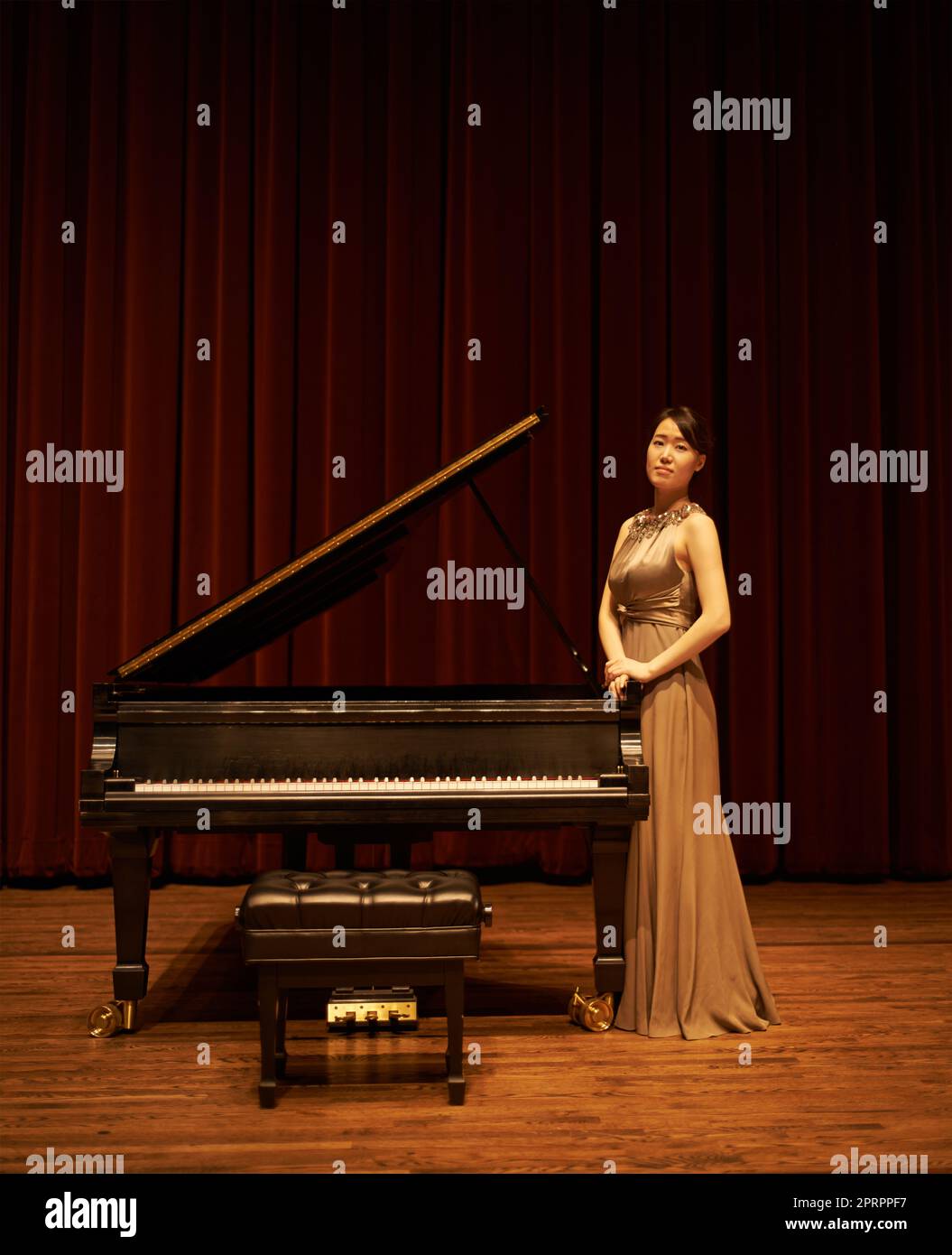 Shes die Hauptattraktion: Eine junge Frau, die am Ende eines musikalischen Konzerts an ihrem Klavier steht. Stockfoto