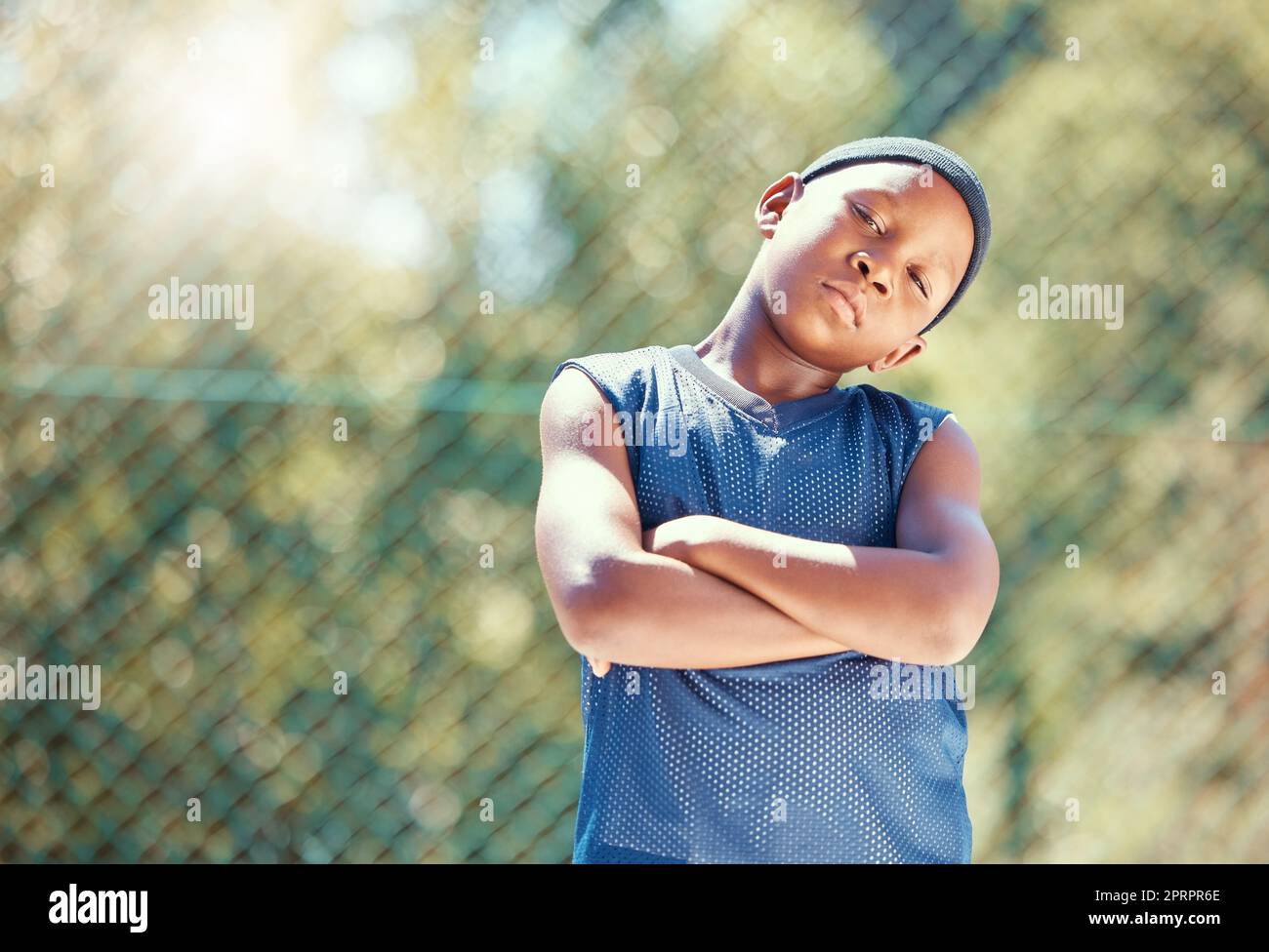 Kind, Basketball und eine ernsthafte Einstellung mit einem schwarzen Jungen, der mit verschränkten Armen steht und bereit ist, draußen zu spielen. Stolzes, selbstbewusstes und cooles Kind, das auf der Straße herumläuft und bereit ist, sich gegen Mobbing zu wehren Stockfoto