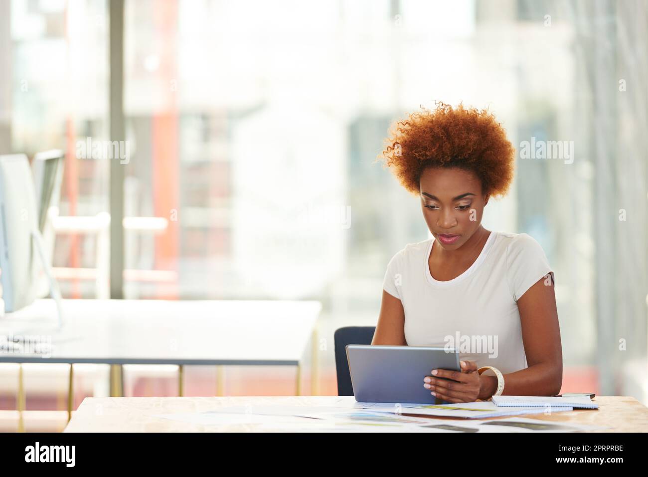 Eine junge Geschäftsfrau, die im Büro ein digitales Tablet benutzt. Stockfoto