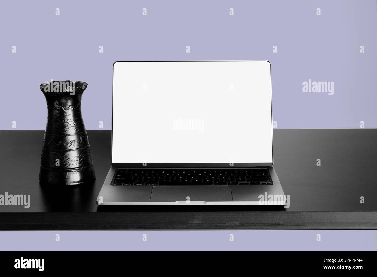 Laptop-Modell auf schwarzem Holztisch mit wechselbarem Desktophintergrund. Mit schwarzer Vase und lila Hintergrund Stockfoto