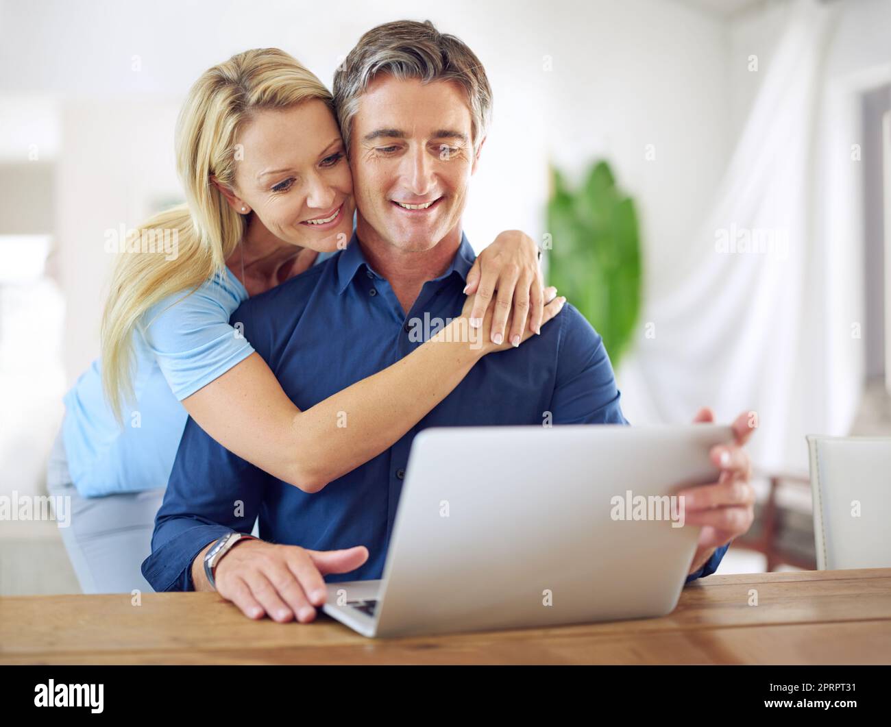 Ich habe unseren Date Night geplant, ein glückliches reifes Paar, das zu Hause einen Laptop benutzt. Stockfoto