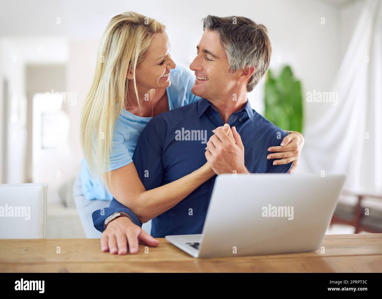 Unser Urlaub ist ausgebucht, ein glückliches reifes Paar, das zu Hause einen Laptop benutzt. Stockfoto