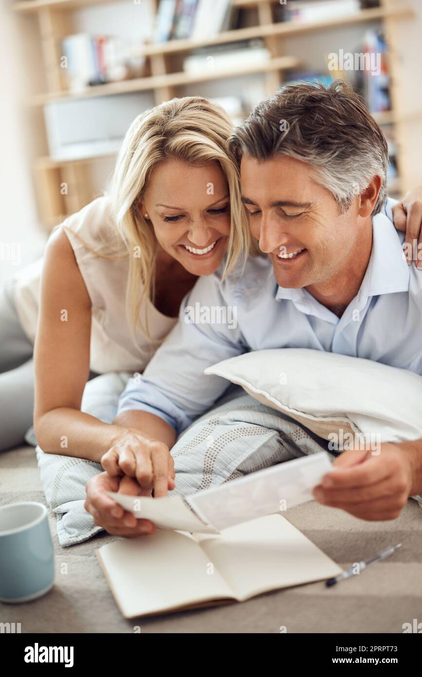 Denken Sie daran: Ein liebevolles reifes Paar, das auf dem Boden ihres Wohnzimmers liegt und Fotos ansieht. Stockfoto