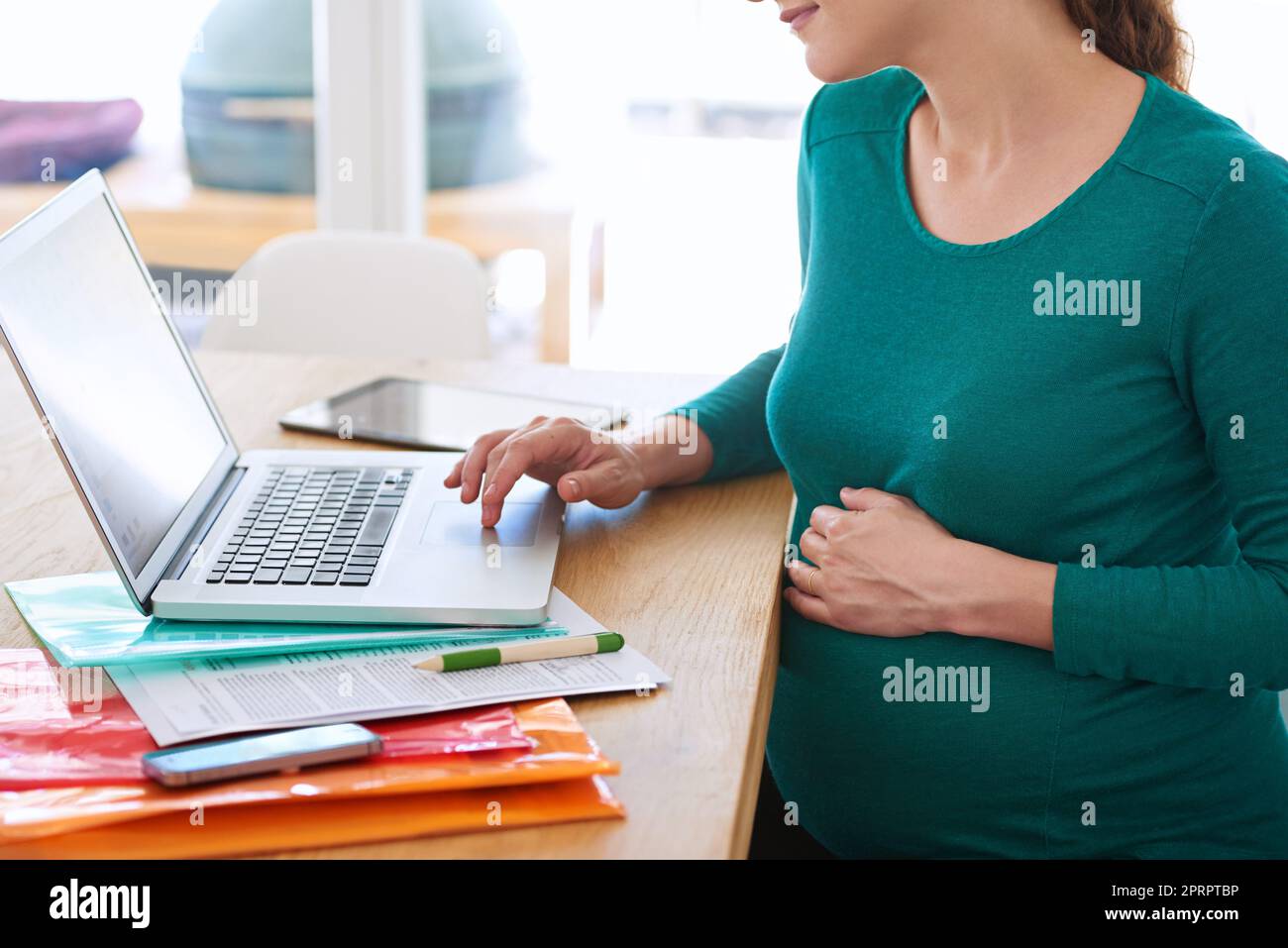 Online-Forschung Was Sie erwarten können, wenn Sie erwarten...eine Schwangere benutzt ihren Laptop zu Hause. Stockfoto