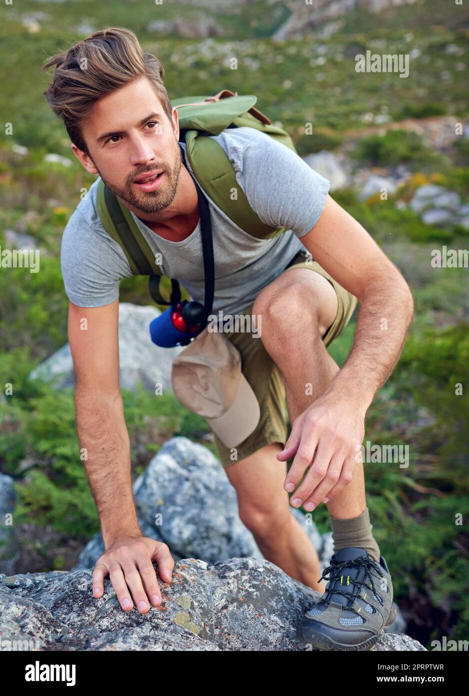 Es geht um den Aufstieg. Ein hübscher junger Mann, der einen Berg bestiegen hat. Stockfoto