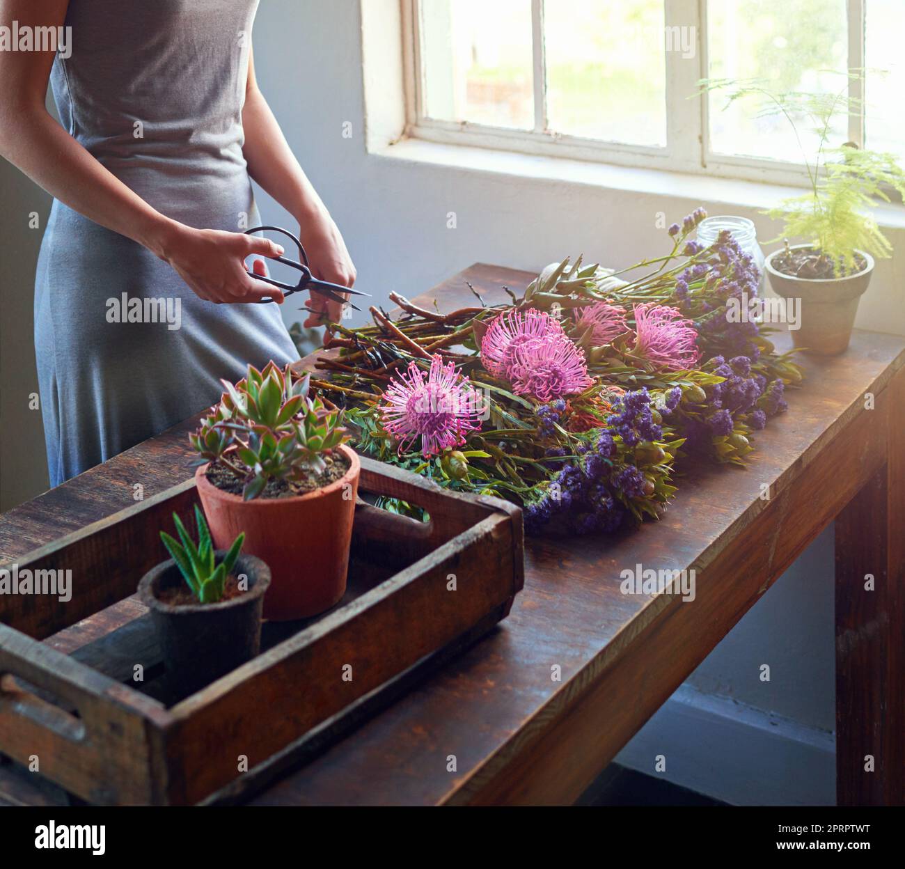 Bringt die Natur ins Haus. Ein hübscher Blumenstrauß wird auf einer Holztheke abgerundet. Stockfoto