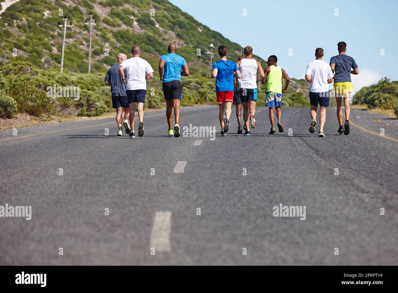 Der Lauf macht mehr Spaß mit Freunden. Rückansicht einer Gruppe von Männern, die einen Marathon laufen. Stockfoto