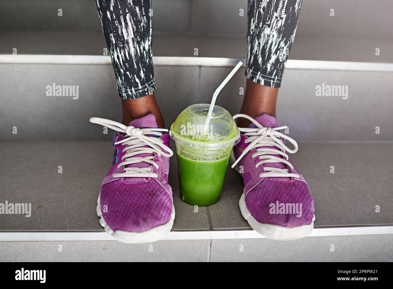Die einzigen zwei Dinge, die Sie für ein gutes Training brauchen: Eine Tasse Saft zwischen einer weiblichen Athleten Füße. Stockfoto