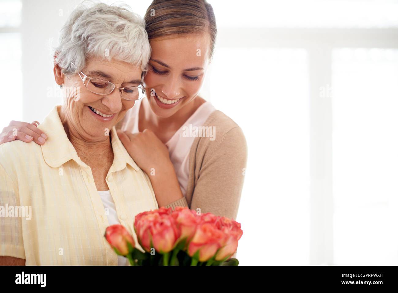 Eine junge Frau, die ihrer Mutter einen Strauß Rosen gab. Stockfoto