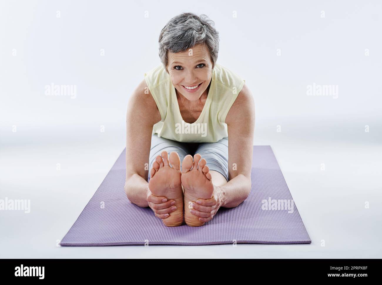 Ich mache meinen Yoga. Ganzkörperportrait einer attraktiven Frau, die sich vor dem Yoga dehnt. Stockfoto