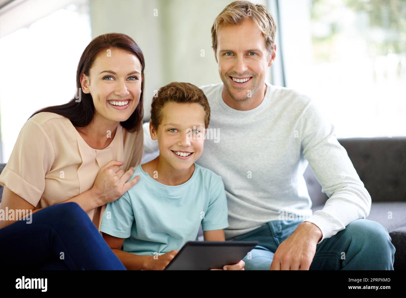 Online-Zeit für die Familie. Porträt einer Familie, die mit einem digitalen Tablet auf dem Sofa sitzt. Stockfoto