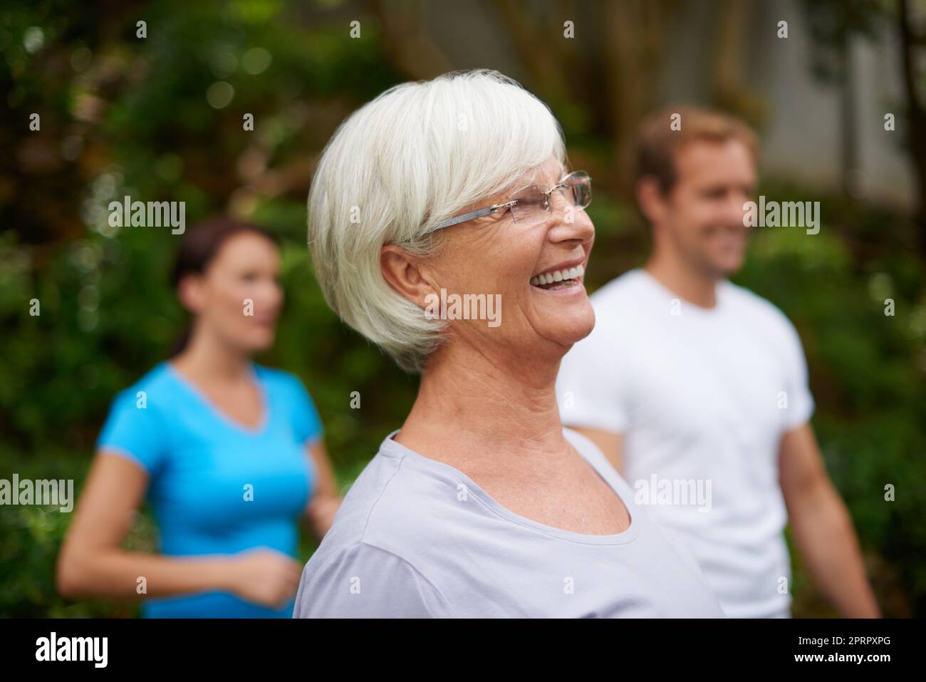 Gesund und fit bleiben. Eine ältere Frau, die im Freien mit anderen Mitgliedern der Fitnessklasse lacht. Stockfoto